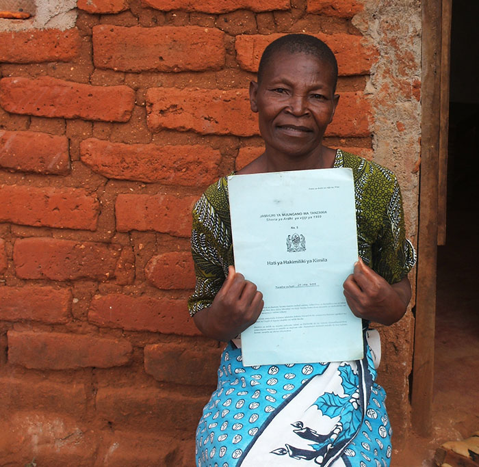 Anna Mdeka proudly holds up her certificate of customary right of occupancy (CCRO).
