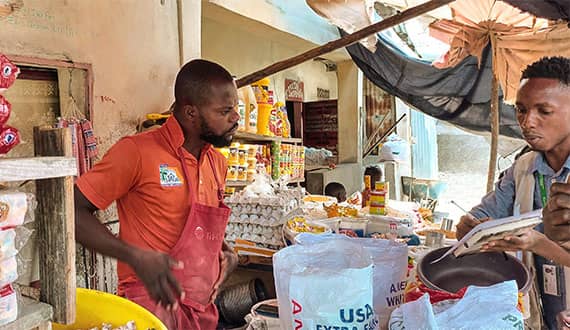 Josef Quetal (age 27) operates a food stall in the Ti Ayiti market, Cité Soleil, Haiti.